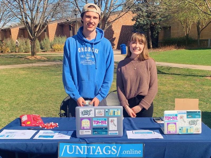 Photo of Ben Frey and Eleanor Harrison at a table showcasing Unitag stickers